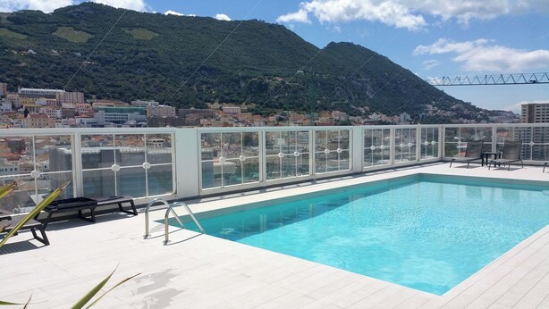 Una piscina en la azotea con vistas a la ciudad y montañas.