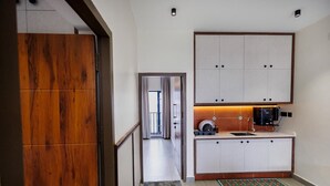 Une cuisine compacte avec des meubles blancs, une machine à café et un petit plan de travail.