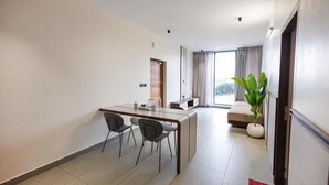 Une chambre d’hôtel moderne dotée d’un coin repas, d’un canapé et d’une grande fenêtre.