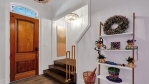 Eine Treppe mit Holzstufen und Messinggeländern, die zu einer Empore mit einer Chandelüster und einem Kranz auf einem Regal führt.