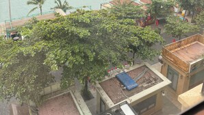 Une vue d’une zone côtière avec plusieurs bateaux sur l’eau, des palmiers et un bâtiment doté d’un toit en tuiles et d’une terrasse.