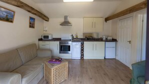 A compact living space with a kitchenette, a sofa, and a small table. - Tranquil Cottage in a Countryside (Ashford)