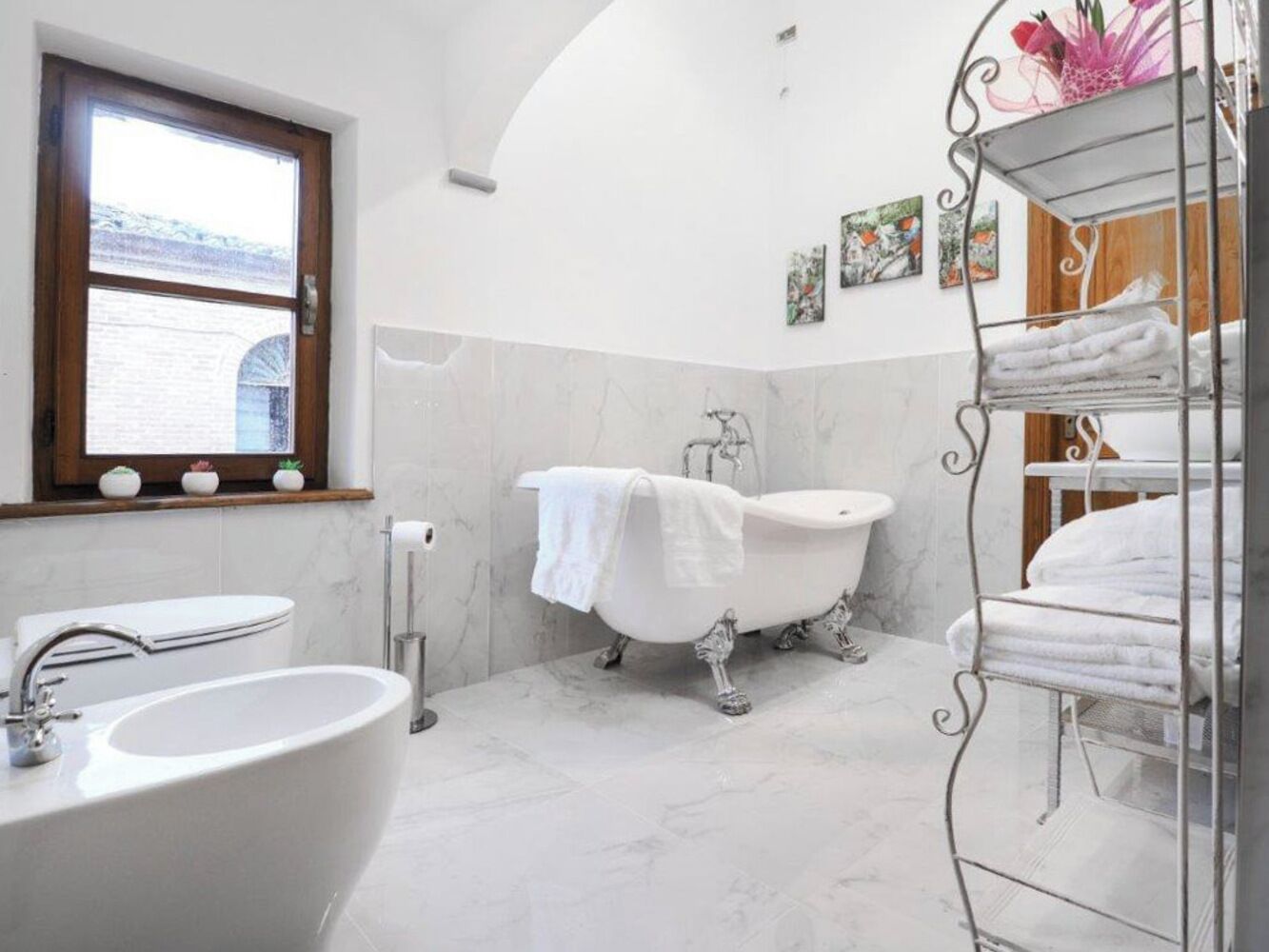 A bathroom with a freestanding bathtub, a large sink, and a window with a view of a building.