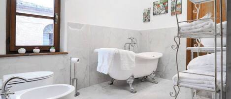 A bathroom with a freestanding bathtub, a large sink, and a window with a view of a building.