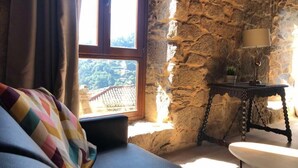 A cozy room with a stone wall, a window with a view, a sofa, and a table with a lamp. - Villa in the Ribeira Sacra, O Batuxo (Pantón (Lugo))