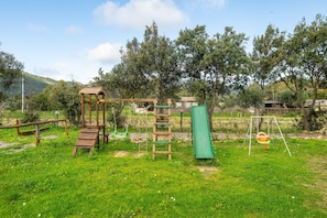 A playground with a swing set, a slide, and a climbing structure. - Mia Rooms: Double Room with Private Patio (Villasimius)