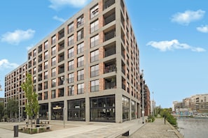 Un immeuble à plusieurs étages doté d’une architecture moderne, avec des balcons et de grandes fenêtres.