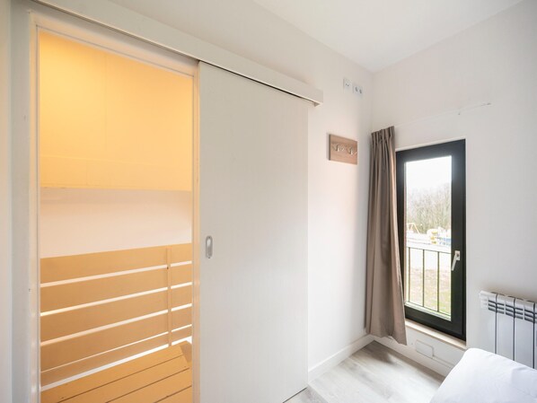 Ein Zimmer mit einer Schiebetür, einem Vorhangfenster, einem Heizkörper und einem kleinen Schild an der Wand.