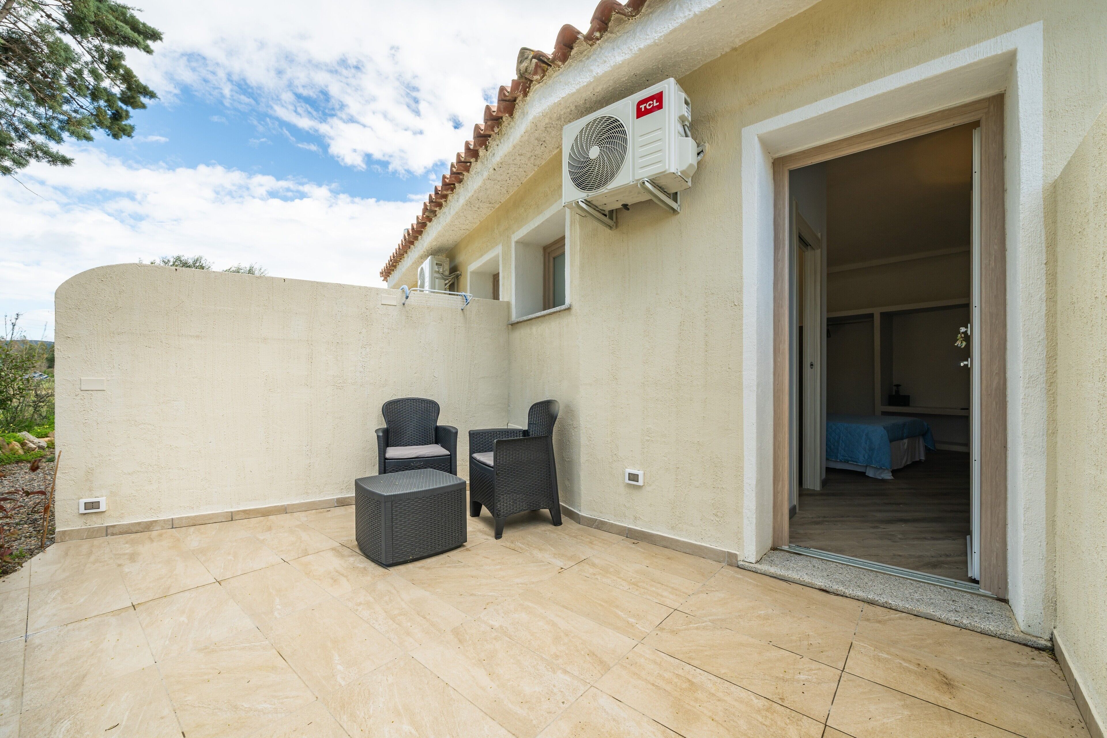 Un patio al aire libre con dos sillas de mimbre, una mesita y un ventilador de techo.