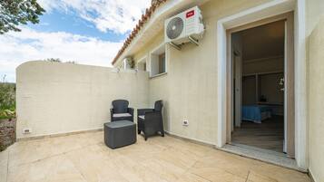 Un patio al aire libre con dos sillas de mimbre, una mesita y un ventilador de techo.