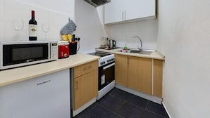 Una cucina compatta con forno a microonde, piano cottura e lavello.