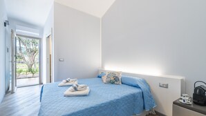 A bedroom with a bed, a bedside table, a window, and a door. - Mia Rooms: Double Room Three with Private Bathroom (Villasimius)