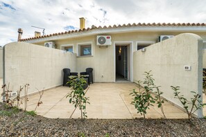 Una casa con un patio, mobiliario exterior y una puerta que da al interior.