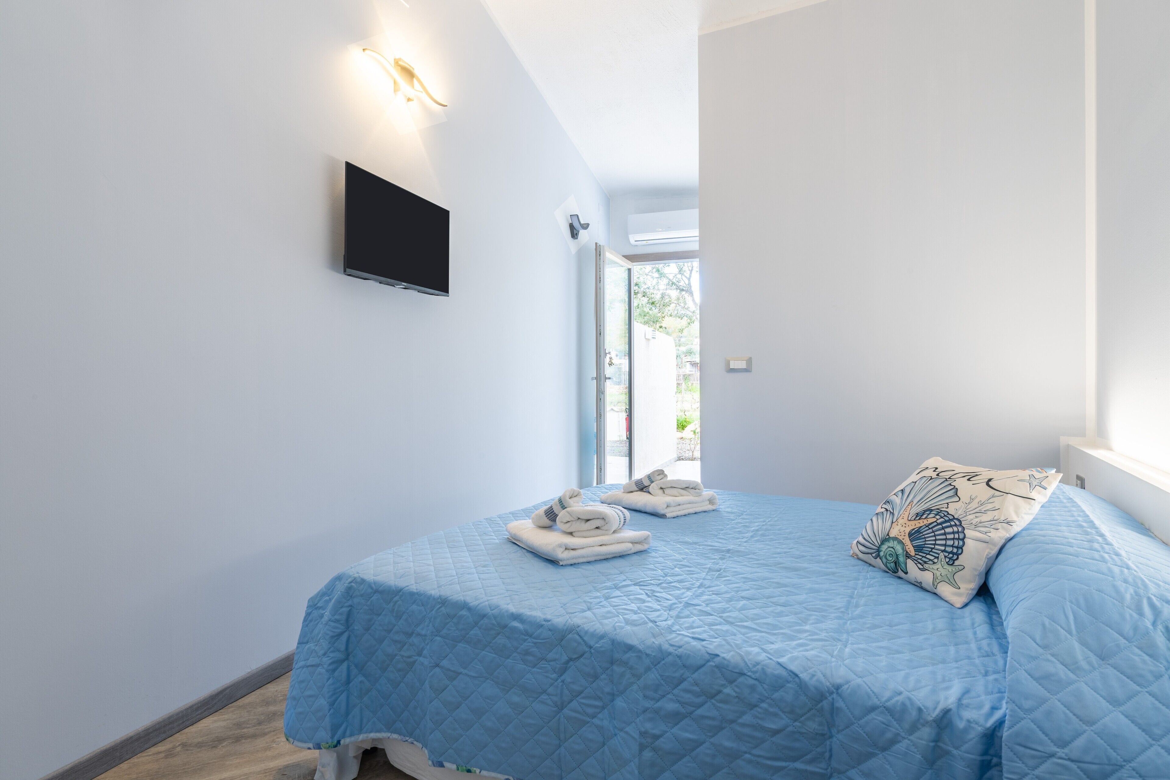 Une chambre à coucher avec un lit, un téléviseur à écran plat et une fenêtre.