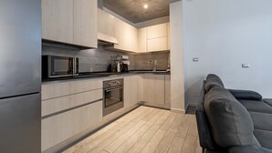Eine moderne Küche mit hellen Holzschränken, Edelstahlgeräten und einer grauen Arbeitsplatte.