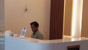 Un comptoir d’accueil avec une enseigne indiquant « RÉCEPTION », un ventilateur de plafond et un panneau décoratif vertical en bois.