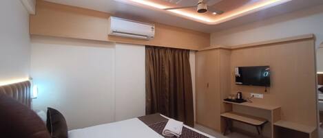 A hotel room with a bed, a TV, a desk, and a wardrobe.