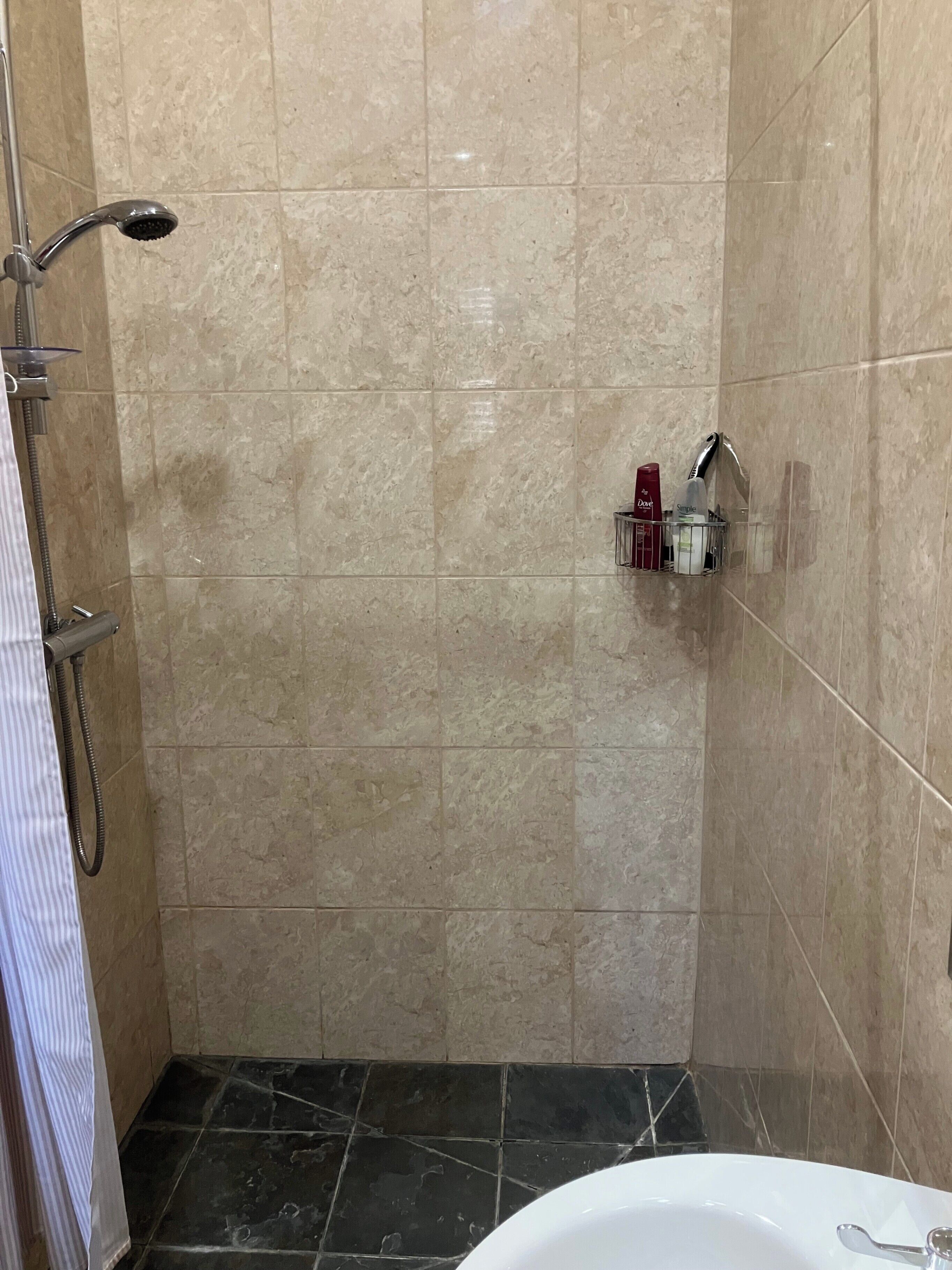 Un baño con ducha, lavabo y toallero.