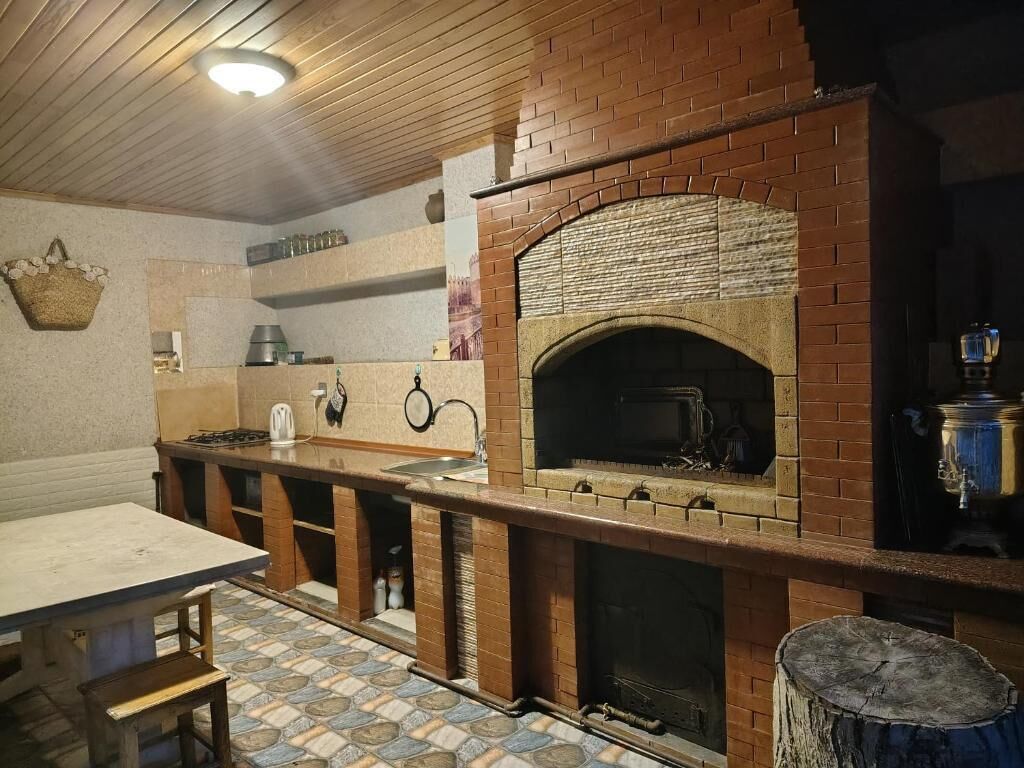 Une cuisine avec un four en briques, des armoires en bois et un sol carrelé.