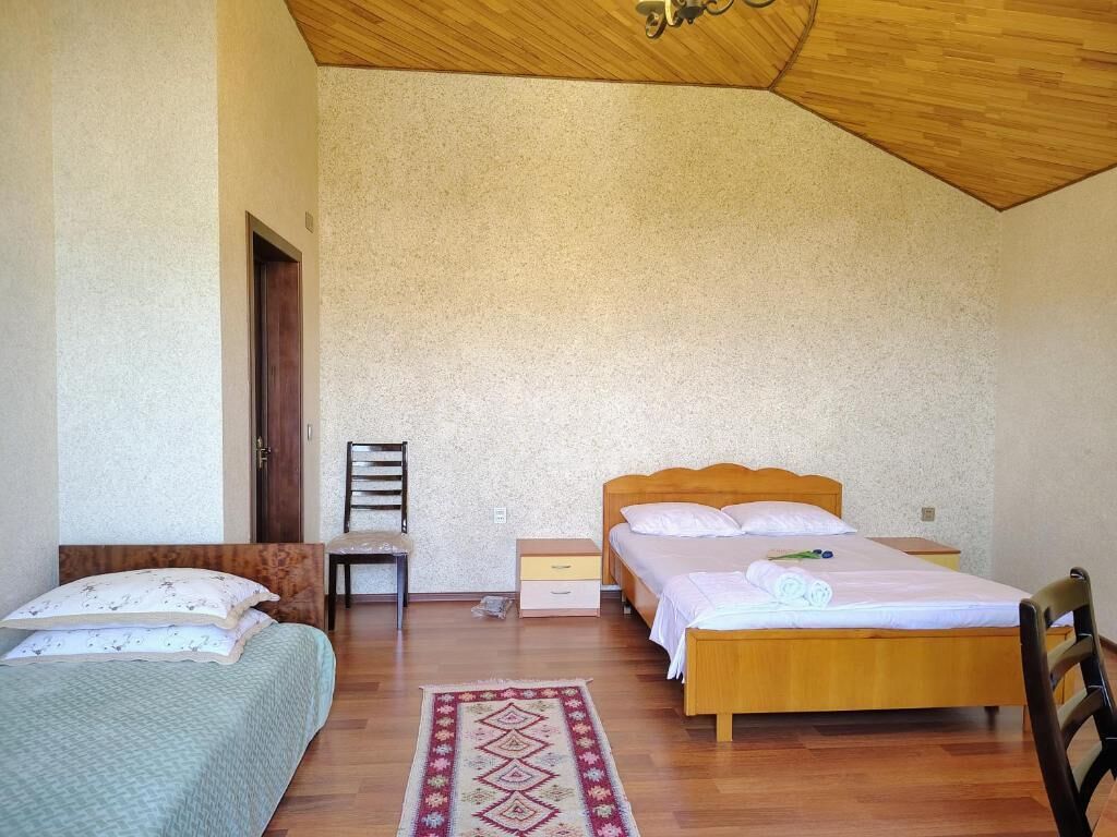 Quarto com duas camas, teto de madeira e tapete estampado.