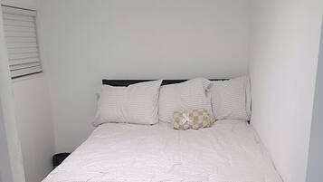 A bedroom with a bed, a ceiling fan, and a carpeted floor.