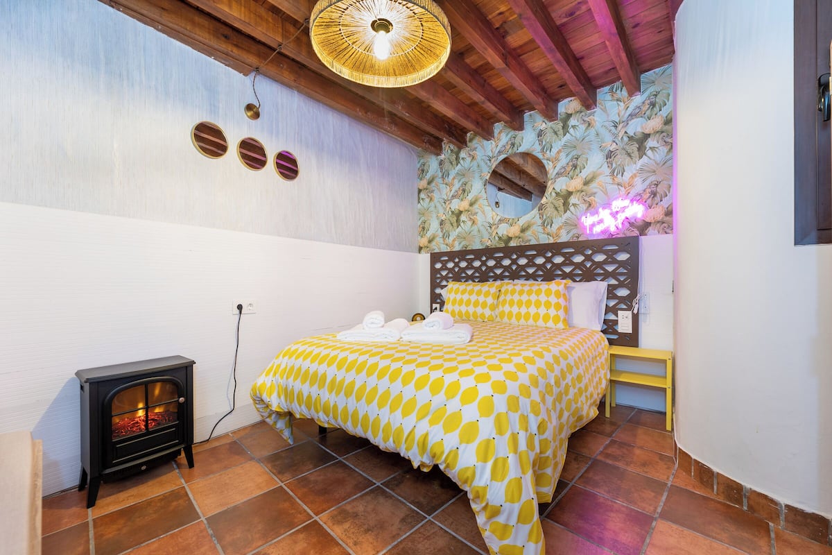 A bedroom with a bed, a small heater, and a decorative wall.
