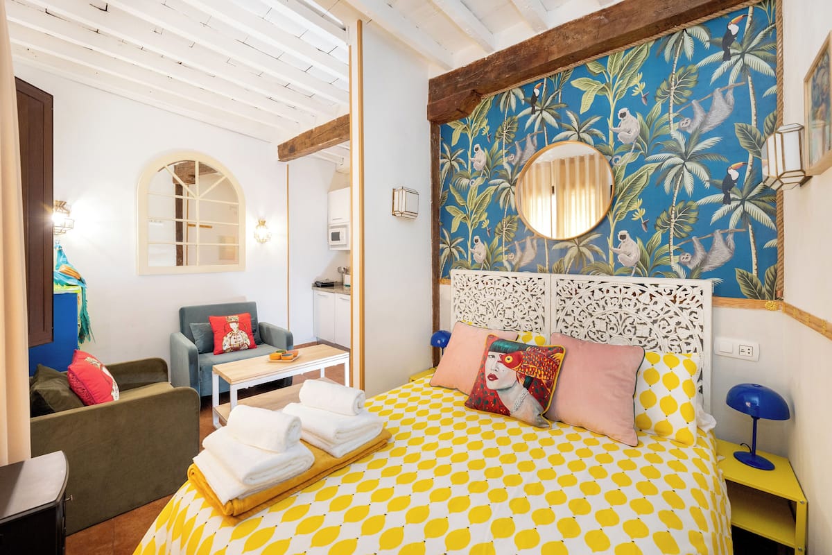 A room with a bed, a sofa, a table, and a chair.