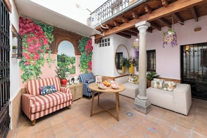 Eine überdachte Terrasse mit zwei Sofas, einem runden Tisch und einer Wand mit Pflanzen.
