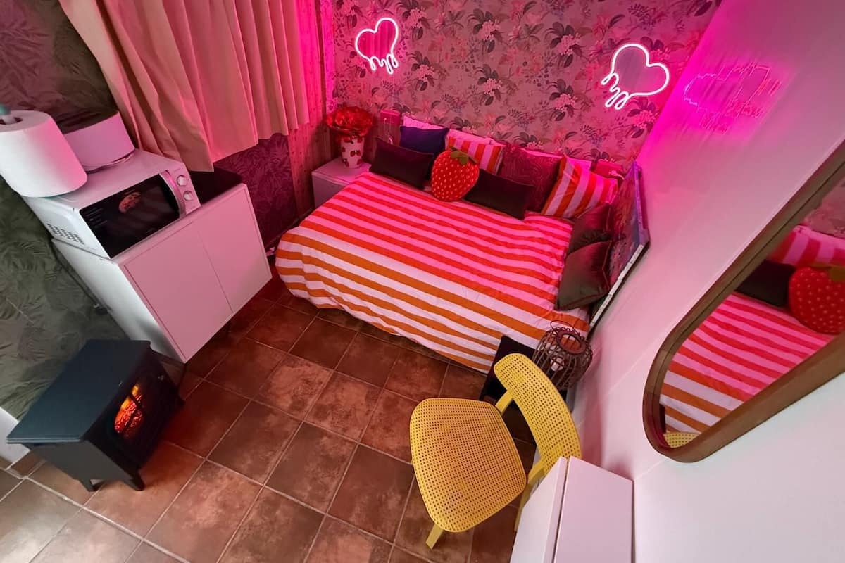 A bedroom with a bed, bedside table, lamp, and a mirror.