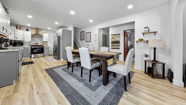 Una cocina moderna con armarios blancos, una mesa de comedor de madera y una alfombra blanco y negro.