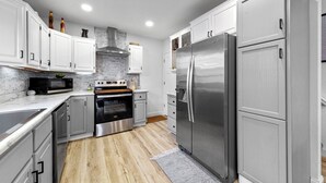 Una cocina moderna con armarios blancos, electrodomésticos de acero inoxidable y suelo de madera.