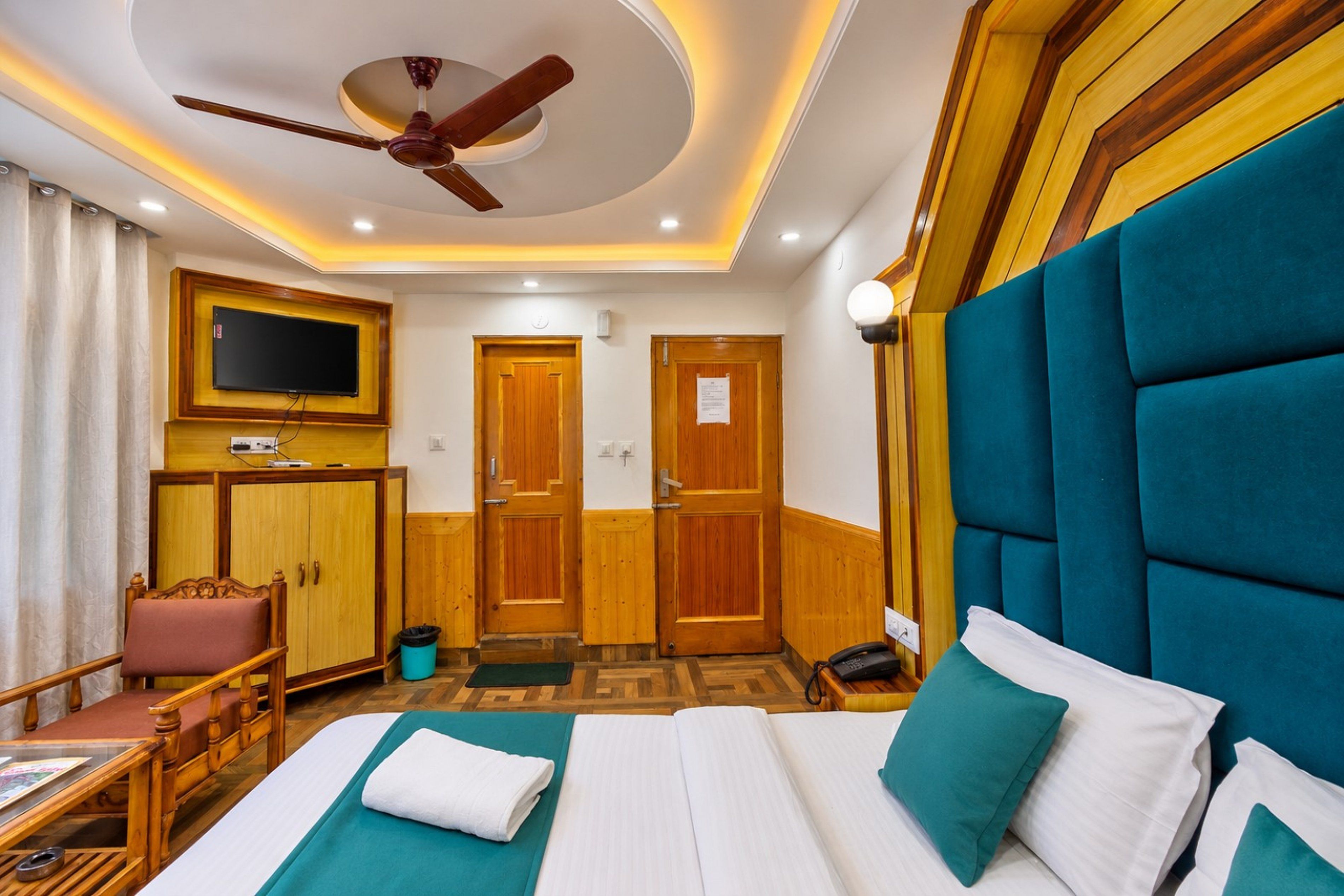Une chambre d’hôtel équipée d’un lit, d’une télévision, d’un bureau et d’un ventilateur de plafond.