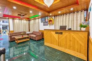 A reception area with a wooden reception desk, two sofas, a coffee table, and a chandelier. - Hotel Sunlight Manali (Manali)