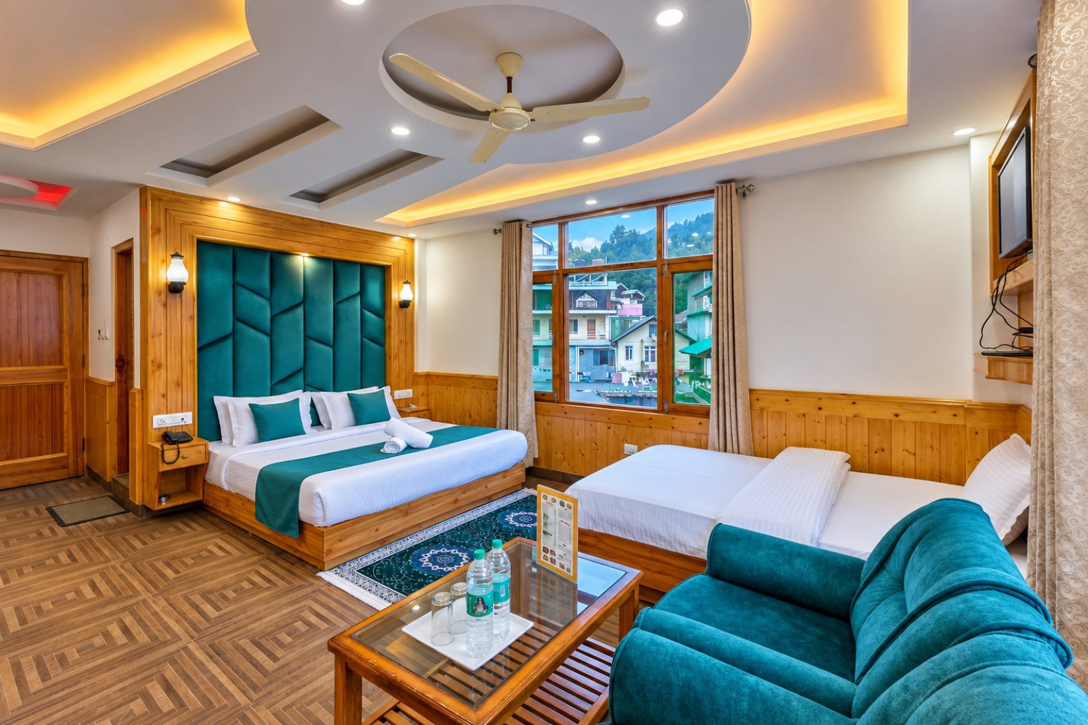A hotel room with a large bed, a sofa, a coffee table, and a view of the city through the window.