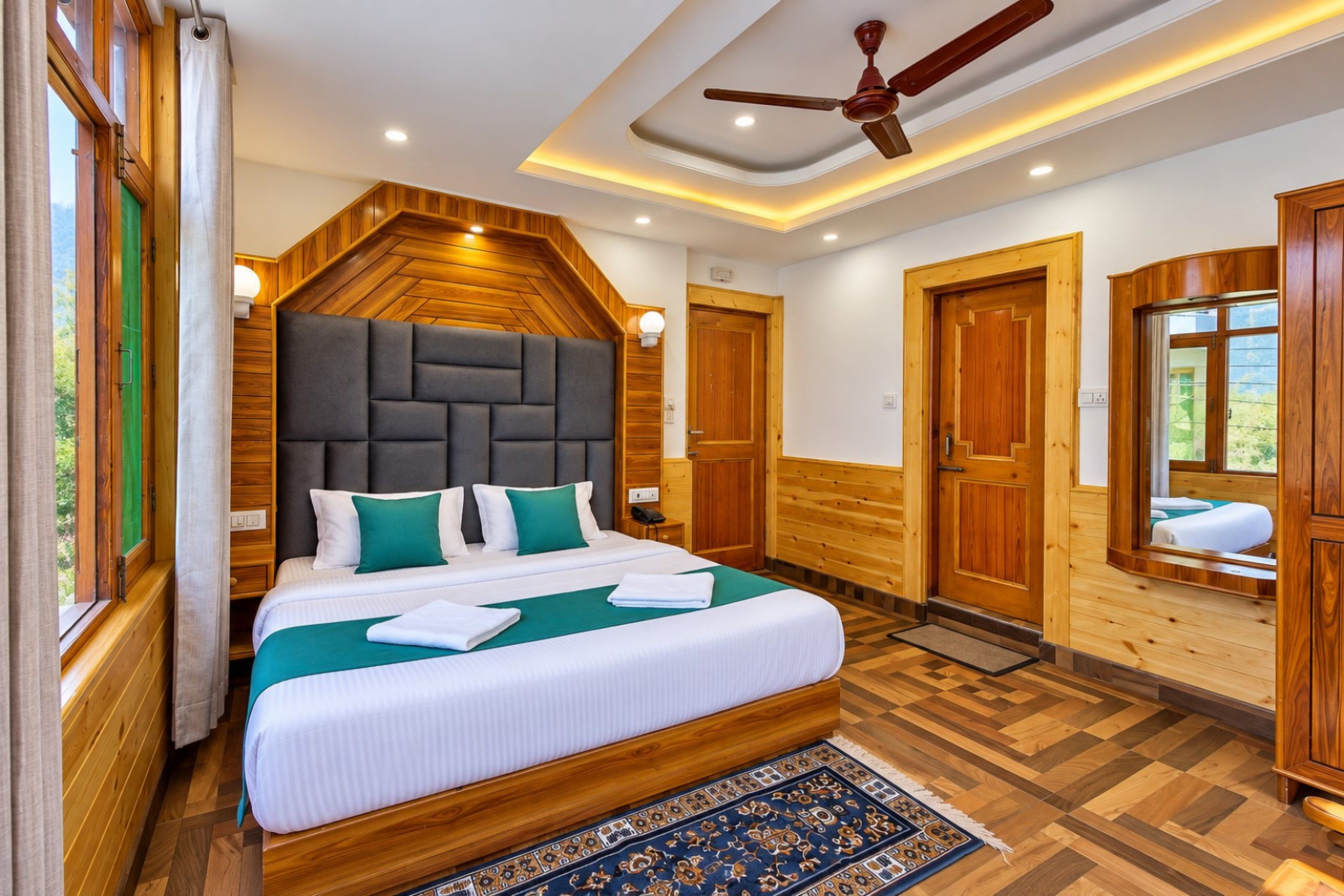 Une chambre d’hôtel avec un grand lit, des murs en bois, un ventilateur de plafond et une vue sur l’extérieur.