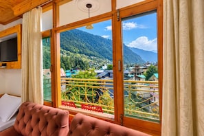 Quarto com uma grande janela que oferece vista para uma paisagem montanhosa.