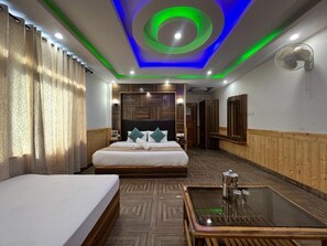 Habitación de hotel con cama, una mesita, techo con iluminación circular, paneles de madera y un ventilador.