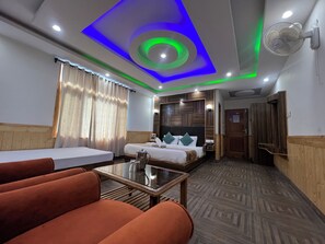 Habitación de hotel con cama, sofá, mesa e iluminación LED en el techo.