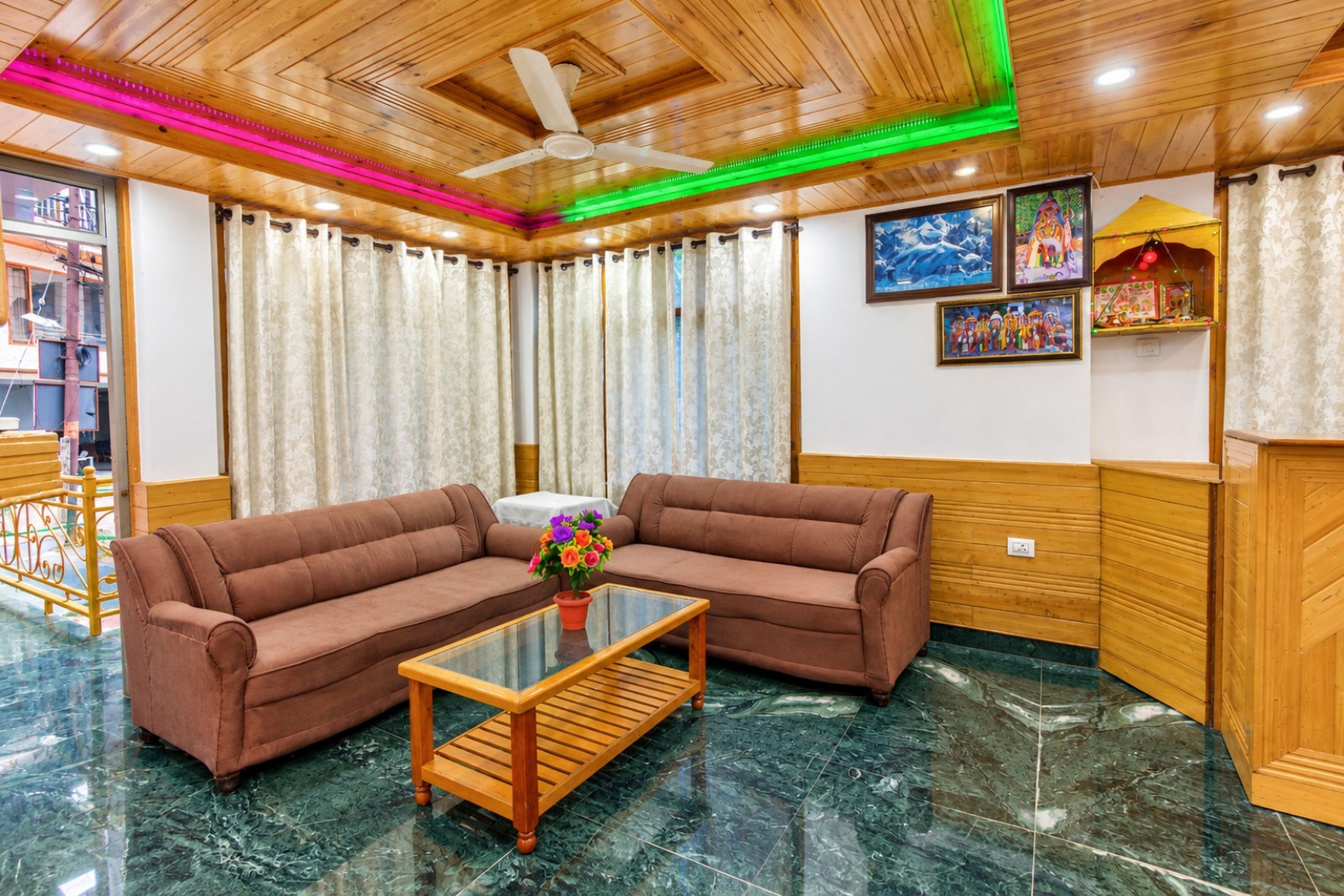 A room with a brown sofa set, a glass coffee table, and a ceiling fan.