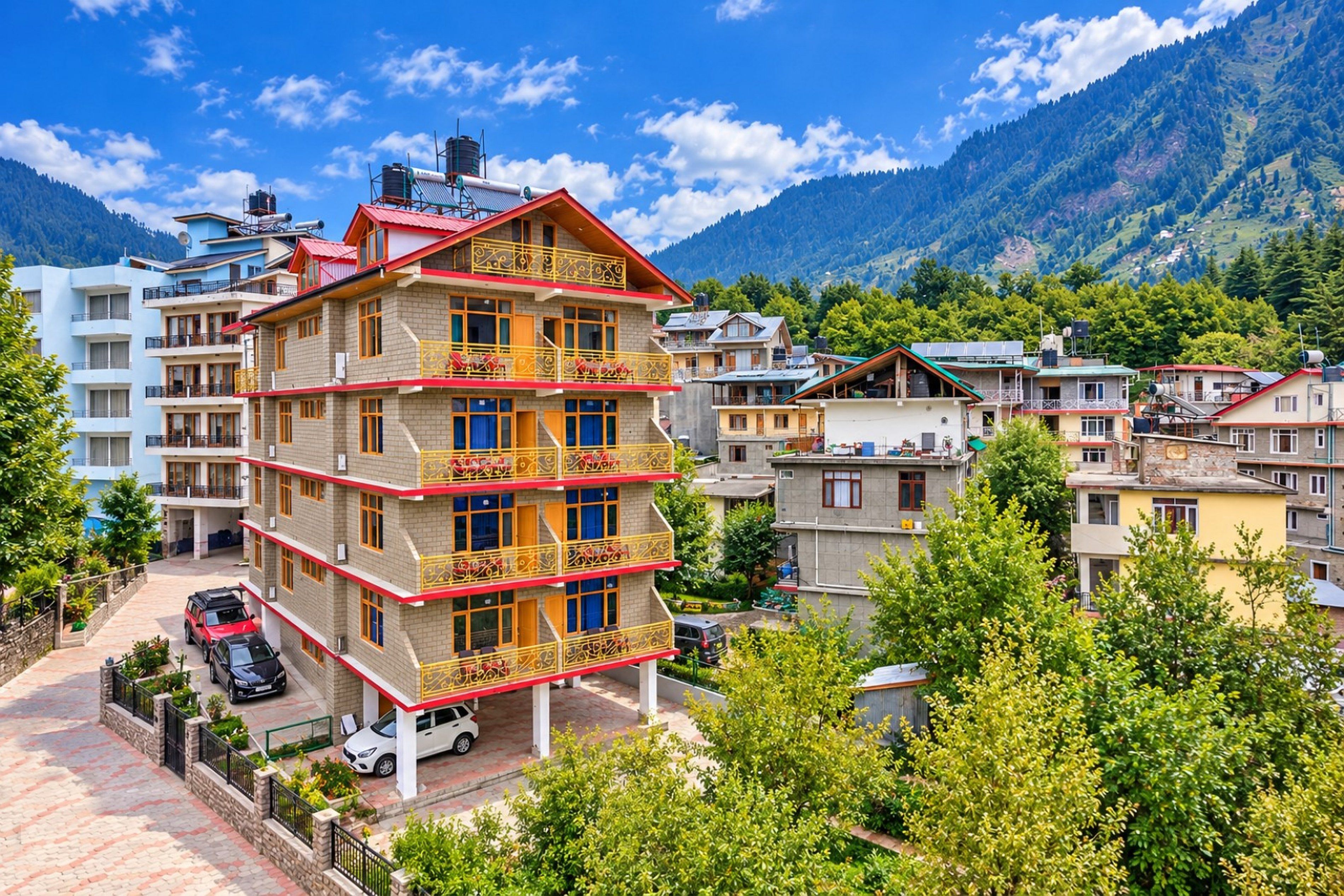 Un hôtel à plusieurs étages, doté de balcons, situé dans une région montagneuse, avec des arbres et d’autres bâtiments en arrière-plan.