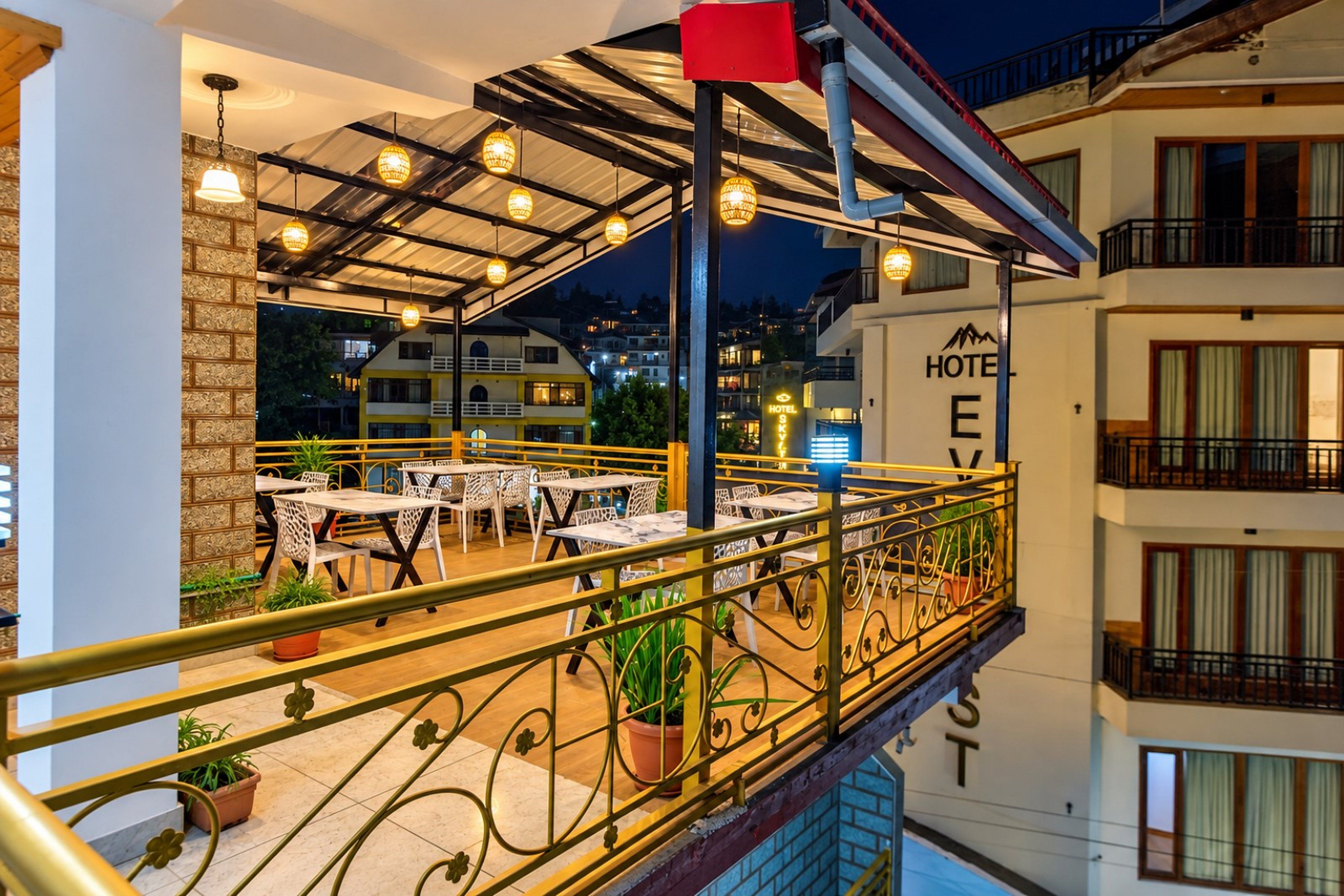 A hotel balcony with outdoor seating and a view of the surrounding buildings.