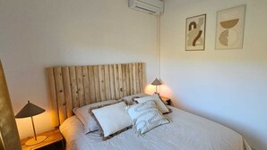 Un dormitorio con cabecera de madera, dos lámparas de noche y dos obras de arte abstracto en la pared.