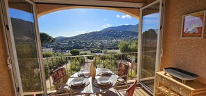 Un balcone con un tavolo apparecchiato per quattro, affacciato su un paesaggio montano suggestivo.