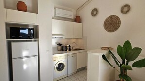 Cocina compacta con refrigerador, microondas, lavadora y pileta.
