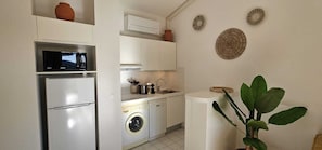 Eine kleine Küche mit Kühlschrank, Mikrowelle, Waschmaschine und Spüle.
