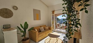 Ein gemütliches Wohnzimmer mit einem Rattan-Sofa, einem kleinen Tisch und einer Topfpflanze.