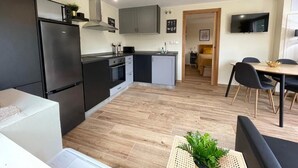 Una cucina moderna con forno a incasso, frigorifero e zona pranzo con tavolo e sedie.