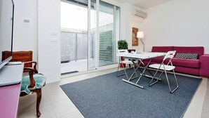 A modern living room with a dining table, chairs, a red sofa, and a laptop on a desk. - People's Square Apartment (Roma)