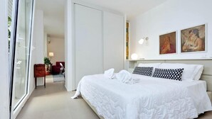 A bedroom with a large bed, white walls, and two paintings. - People's Square Apartment (Roma)