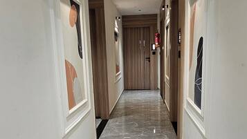 A hallway with marble flooring, wooden doors, and wall-mounted light fixtures.